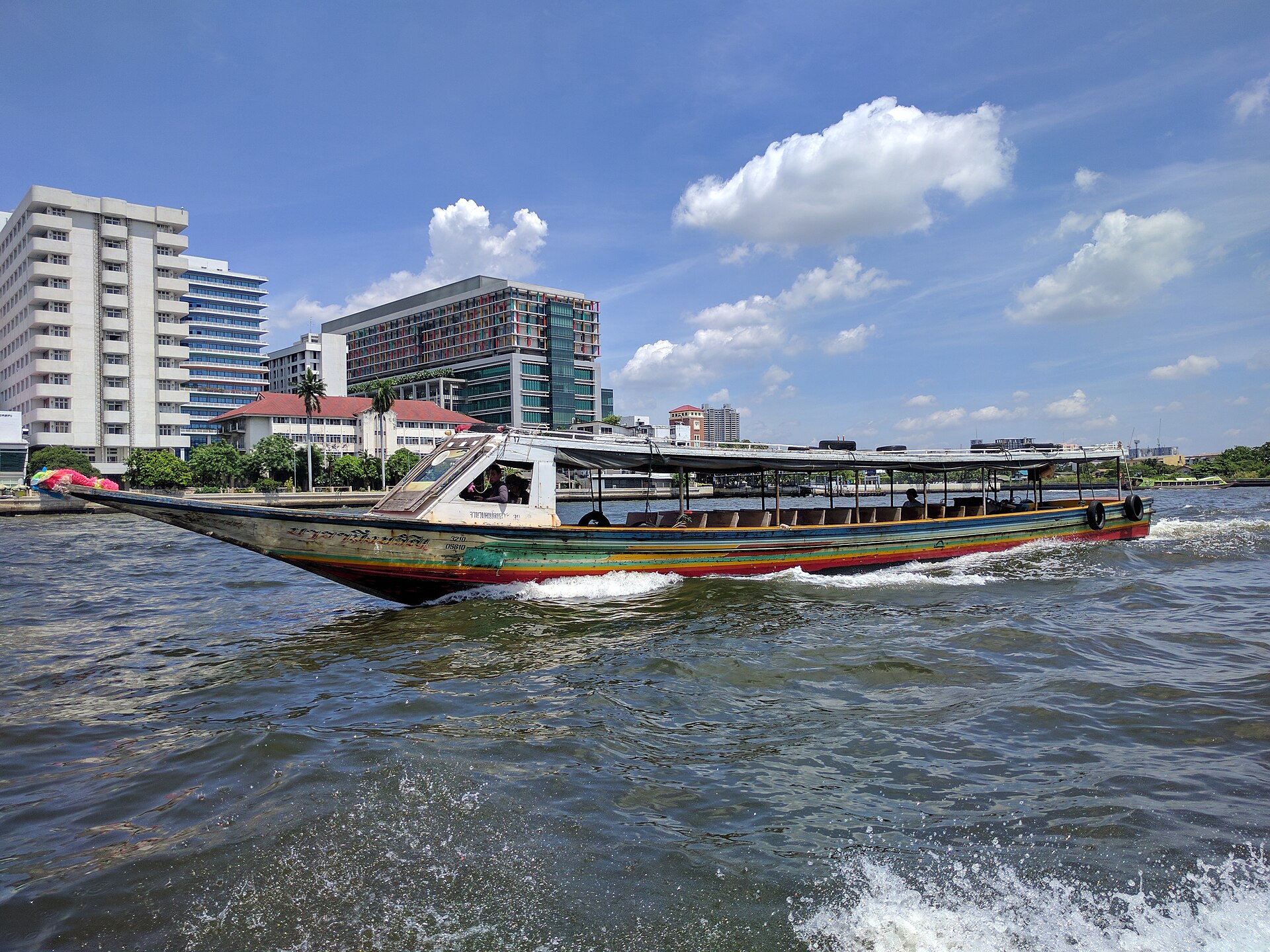Long-tail boats and riverside temples along the Chao Phraya River in Bangkok, Thailand