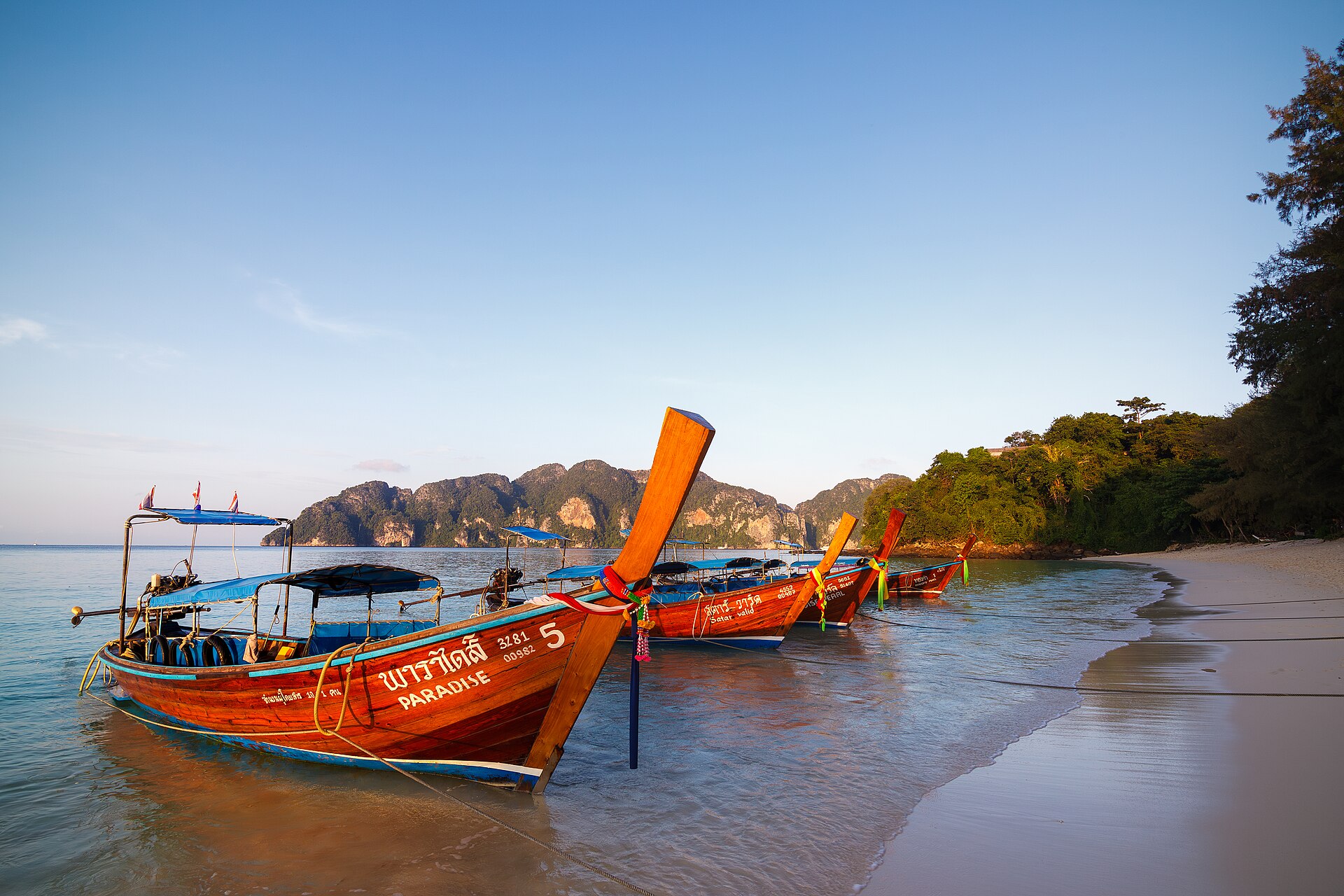 Traditional Thai longtail boat on turquoise water beside limestone cliffs in southern Thailand